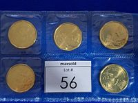Five $1 coins in sealed packaging displayed on blue background with lot number card.