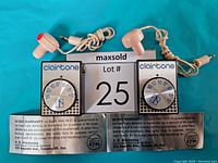 Two Clairtone Mini Hi-Fi AM transistor radios with circular tuning dials and connected earbuds on blue background, including original warranty paperwork.
