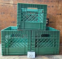 Three green plastic milk crates stacked; one on top of another two stacked crates, showing lattice panel sides and handles