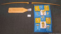 Full view of unstrung bow, fish cleaning board, and mushroom identification tapestry textile.