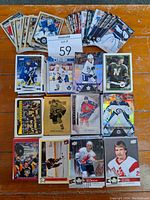 Spread of mostly 90s and early 2000s hockey cards featuring various players in different team uniforms with a MaxSold lot card