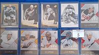 Photo showing all 10 rookie hockey cards encased in clear protective sleeves, featuring various NHL players in different team uniforms from the SP Authentic Rookies series.
