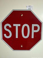 Close-up of the STOP sign showing the reflective red background and white text, octagonal shape with mounting holes.