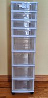 Front view of tall plastic storage unit displaying all eight transparent drawers and castors.
