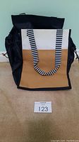 Front view of the Thirty-One color block tote bag showing black, white, and brown panels with striped handles and elastic sides.