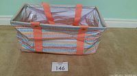 Photo of Thirty-One Medium Utility Tote presumed in Fun Lines pattern showing rectangular shape, colorful geometric pattern, orange carrying straps, and wire support inside.