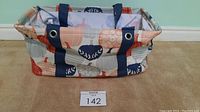 Thirty-One Medium Utility Tote with fall pumpkin design, showing front and side, navy handles, fabric constructed with wire framed shape.