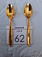 Top view of two gold plated teaspoons showing the bowl side with star shaped cut-out patterns and overall gold finish.