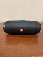 Front view of the black Charge 3 Bluetooth speaker showing the orange logo and fabric design.