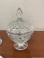 Crystal footed candy dish with diamond pattern and pointed finial lid, on wooden surface