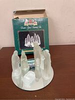 Image showing 7-piece frosted glass nativity set arranged on a circular mirrored base with original Hudson Bay box in background.