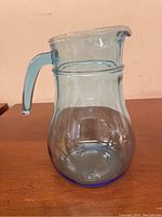 Side view of translucent light blue glass pitcher showing overall shape and handle.