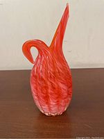Front side view of the red and white swirled ribbed glass pitcher vase showing the handle and overall form.