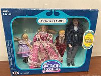 Boxed Victorian Family doll set with four dolls visible - mother, father, and two children in period clothing.