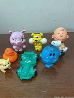 Front view of all seven toy figurines showing various characters and a green toy racecar