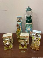 Five vintage Avon perfume bottles with original boxes, including a green lantern-shaped bottle and three others of unique shapes and sizes.