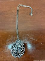 Photo showing the full length of the Guy Vidal Brutalist pewter necklace on a wooden surface.