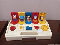Photo showing the vintage Disney Poppin Pals toddler toy with five pop-up character figures visible: Goofy, Figaro the cat, Mickey Mouse, Donald Duck, and Pluto.