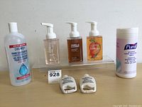 Lot of hand care products including three foaming hand soap bottles, one hand sanitizer gel bottle, one container of sanitizing wipes, and two lotion tubes shown on a clear acrylic riser.