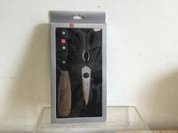 Front side view of the Wüsthof kitchen tool set in original packaging, showing the kitchen shears and two utensils with black handles.