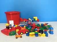 Full lot overview showing the red storage bin with assorted building blocks, cars, and figures arranged in front of a blue background.