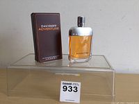 Photo showing the Davidoff Adventure cologne bottle and its original box on a clear box stand.