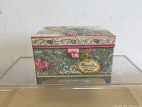Closed floral music box labeled 'Music Box Soaps' on front