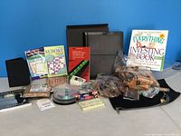 Full lot overview showing portfolio, passport folder, books, puzzles, office supplies, calculator, CD spindle, and wooden keychains