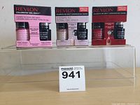 Three packs of Revlon ColorStay Gel Envy nail polish sets on acrylic stand, showing front packaging with visible brand and colors (light pink, beige, red).