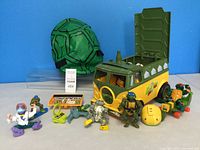 Full lot view of Teenage Mutant Ninja Turtles toys and accessories including vehicle, backpack, figures, and gear
