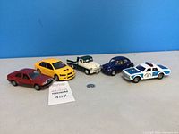 Overview of 5 vintage toy cars on a white surface with a blue background.