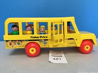 Side profile of vintage Fisher-Price yellow plastic school bus toy with original Fisher-Price people sitting inside visible through open window bars.