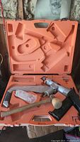 Open orange molded case with Floor Attack 200 stapler and wooden mallet inside