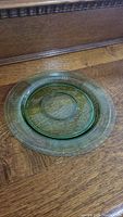 Green translucent plate with textured rim shown on wooden surface under natural lighting.
