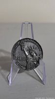 Obverse side of large coin token showing Statue of Liberty and value inscriptions.