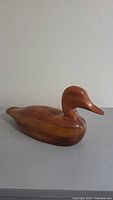 Side profile view of wooden duck decoy showing smooth polished wood finish and carved shape.