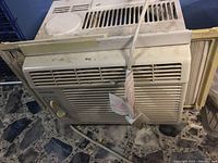 Overall view of the KoolKing window air conditioner with visible vents and power cord on a tiled floor.