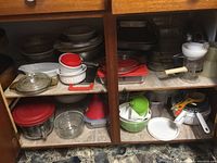 Shelves containing multiple bowls, glass bakeware, and kitchen utensils.