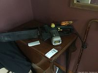 Chainsaw and hand saw and cane placed on a wooden table corner