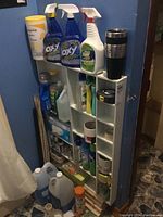 View of cleaning products, storage shelf with various bottles and containers, and a travel mug on top