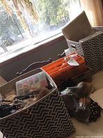 Overview showing three different containers with various craft supplies including twines, beading box, hole punch, and a bag of plastic fruit.