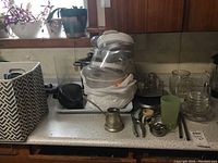 Photo showing kitchen counter with food dehydrator, Magic Bullet blender base, fish poacher, glassware, and small metal utensils.