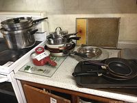 View of assorted cookware on kitchen counters including frying pans, stock pots, teapot, and baking sheets