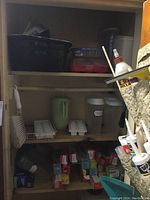 Shelves with large black roaster pan, various plastic containers (red, clear, and white lids), ice trays, green pitcher, clear tumblers, and several boxes of food wrap products.