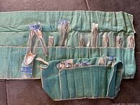Full lot view in green cloth roll showing both sizes of spoons in plastic sleeves