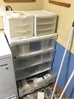 Photo of stacked plastic storage drawer units filled with various plastic storage containers and lids, showing details of containers inside open drawer.