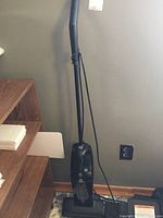 Full view of the upright vacuum cleaner showing handle, base, and power cord.