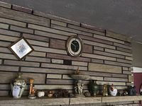 Image showing a stone fireplace mantle with various vases, small figurines, and a wall clock in the background.