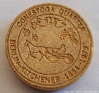 Front side of wooden token showing Conestoga Quarter design with horse carriage and dates 1819 to 1979.
