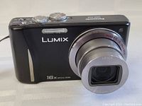 Front view of camera with lens extended showing "Leica" lens and "16x optical zoom" marking.